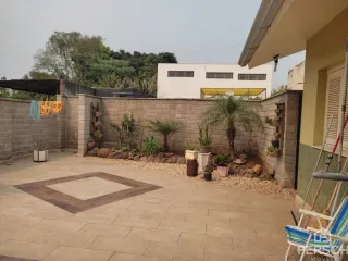 Área externa pavimentada com jardim e muro de contenção.