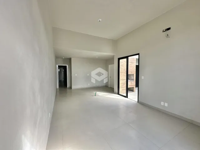 Corredor interno de uma residência moderna com paredes brancas e piso claro.