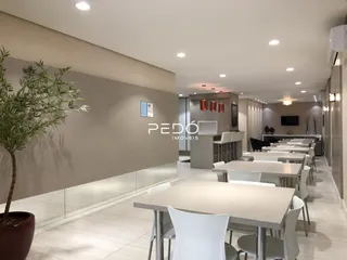 Ambiente interno moderno com mesas e cadeiras em um espaço amplo.