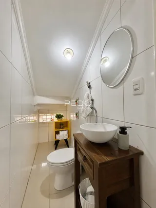Foto de um banheiro com revestimento branco e louças sanitárias.