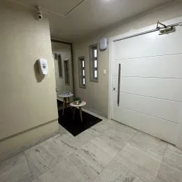 Hall de entrada com piso claro e porta branca.