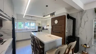 Cozinha moderna com ilha e armários brancos em um ambiente claro.