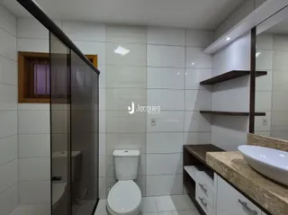 Banheiro moderno com box de vidro e revestimento branco.