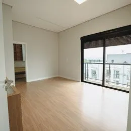 Foto de um cômodo interno com piso de madeira clara e paredes brancas.