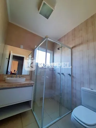 Foto de um banheiro com box de vidro e louças brancas.