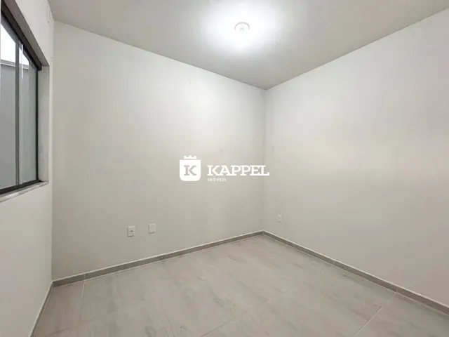 Foto de um cômodo vazio com paredes brancas e piso claro.