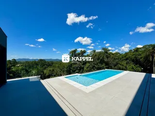 Piscina externa em um terraço com vista para a vegetação exuberante.