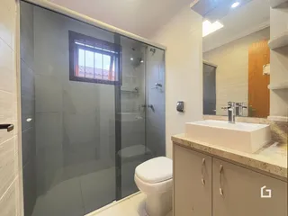 Foto de um banheiro moderno com box de vidro e louças brancas.