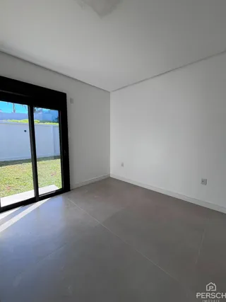 Vista interna de um cômodo com paredes brancas e piso de concreto.