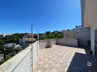Vista de uma área externa com piso de cerâmica e parede branca.