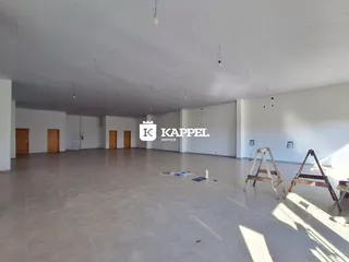 Foto de um ambiente interno amplo e vazio com piso claro e teto branco.