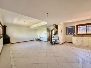 Ambiente interno de uma sala de estar com piso de cerâmica e escadaria.