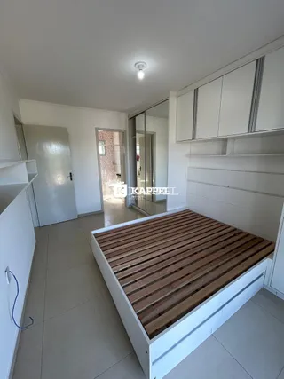Uma foto de um quarto com cama de madeira e armários brancos.