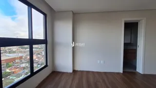 Vista interna de uma sala com piso de madeira e grande janela.