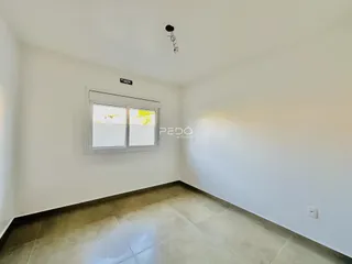 Vista interna de uma sala com paredes brancas e piso de cerâmica.