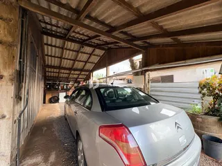Vista interna de uma estrutura rústica com um carro estacionado.