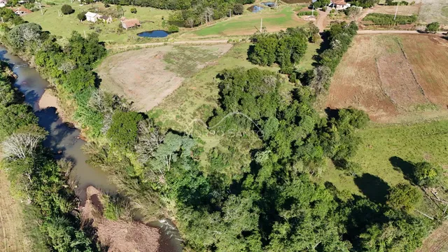 Vista aérea de uma propriedade rural com vegetação densa e áreas de campo.