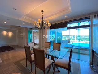 Sala de jantar com mesa de vidro e vista para a piscina externa.