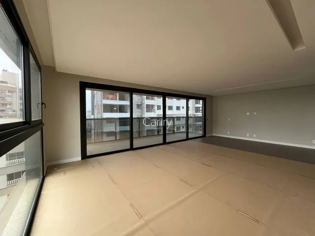 Ambiente interno com grandes janelas que proporcionam vista para edifícios vizinhos.