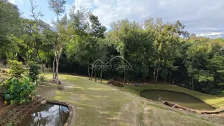 Paisagem externa com gramado, árvores e um pequeno lago em uma propriedade.