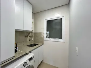 Vista interna de uma cozinha com armários brancos e bancada clara.