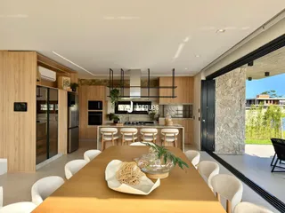 Uma sala de jantar moderna com cozinha integrada e vista para o exterior.