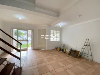 Interior de uma sala com piso de cerâmica e escada visível.