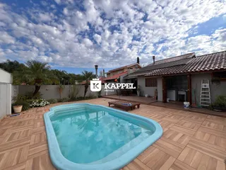Foto de uma piscina externa em um pátio de madeira com vista para uma casa.