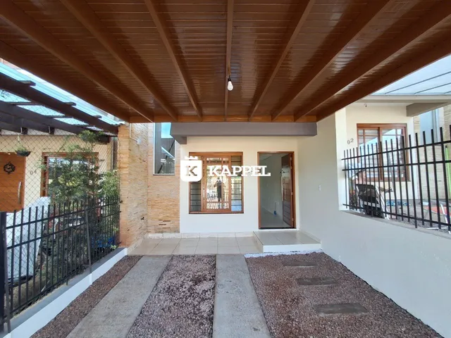 Vista da fachada de uma casa com piso de concreto e estrutura de madeira.