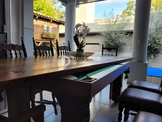 Vista de uma área externa com uma mesa de madeira e vegetação.