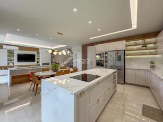 Interior de uma cozinha moderna com ilha de mármore e sala de jantar.