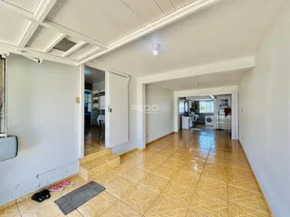 Hall de entrada com piso de cerâmica clara e teto com vigas brancas.