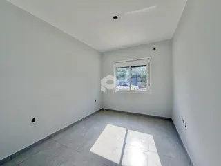 Vista de um ambiente interno com paredes brancas e piso de cerâmica.