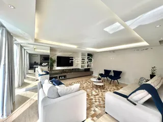 Sala de estar moderna com decoração clara e grandes janelas.