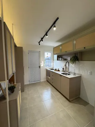 Uma cozinha moderna com armários claros e piso de cerâmica.