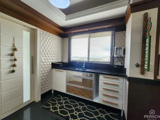 Foto de uma cozinha com armários brancos e bancadas escuras em um apartamento.