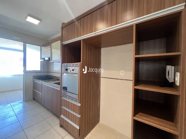 Interior de uma cozinha com armários de madeira e piso cerâmico.