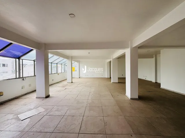 Vista interna de um espaço amplo com piso de cerâmica e colunas brancas.