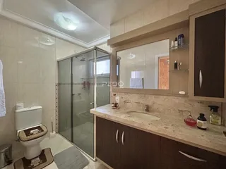 Banheiro com box de vidro e bancada de mármore.