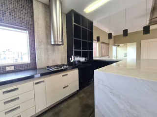 Foto de uma cozinha moderna com armários brancos e bancadas escuras.