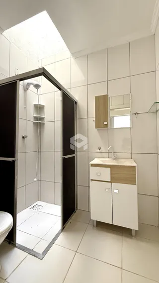 Foto de um banheiro com box de vidro e bancada de madeira clara.