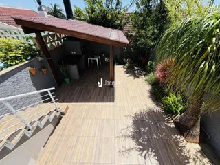 Área externa com piso de cerâmica e vegetação exuberante.