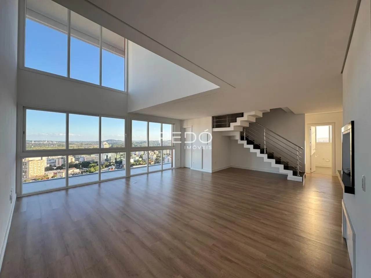 Uma sala de estar ampla com grandes janelas que oferecem uma vista panorâmica da cidade.