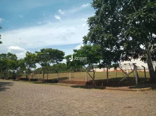 Vista externa de um terreno com gramado e árvores.