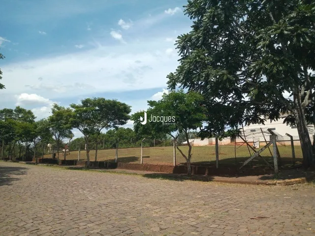 Vista externa de um terreno com gramado e árvores.