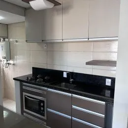 Foto de uma cozinha mostrando armários superiores e bancada escura.