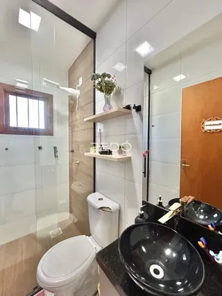 Foto interna de um banheiro com revestimento de cerâmica e box de vidro.