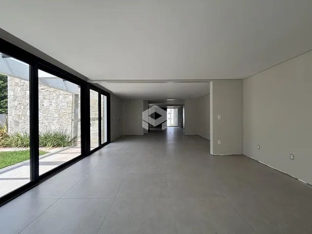 A foto mostra um corredor interno de uma residência com grandes janelas.