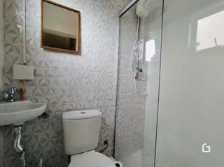Foto de um banheiro com azulejos brancos e louças sanitárias.