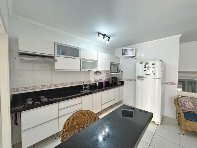 Vista da cozinha moderna com armários brancos e bancadas escuras.